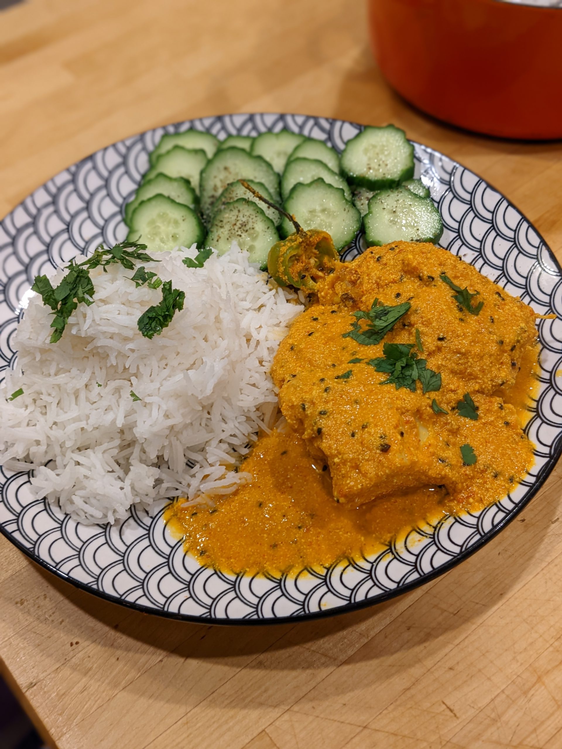 Fish curry plated with white rice and cucumbers